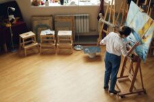 Kunstner maler ved et staffeli i et lyst atelier