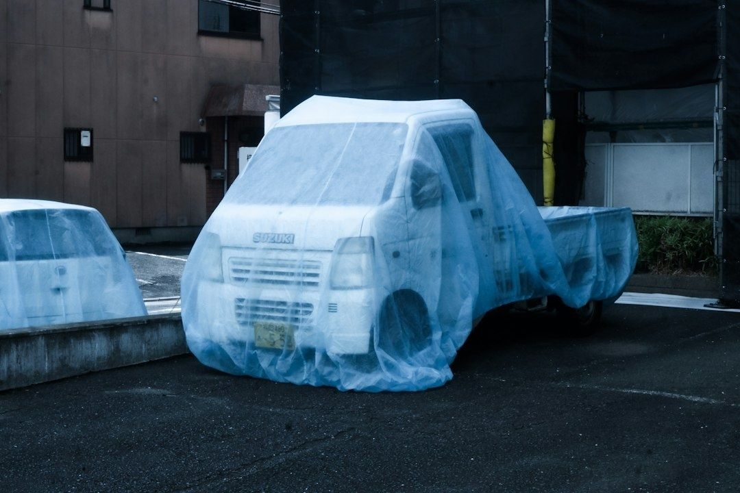 Liten lastebil dekket med plast på en parkeringsplass